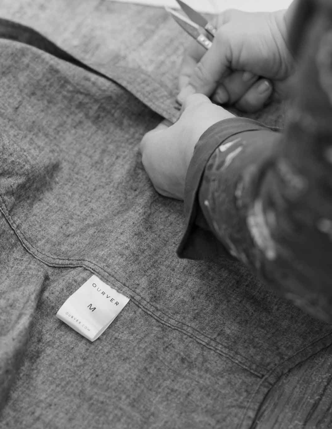 Hands stitching buttons on to ourver shirt